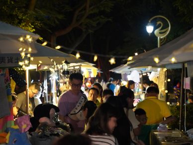 Night market bustling with people under string lights and tents.