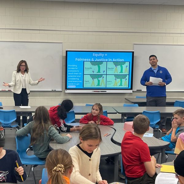 Two instructors present on equity while kids work in class.
