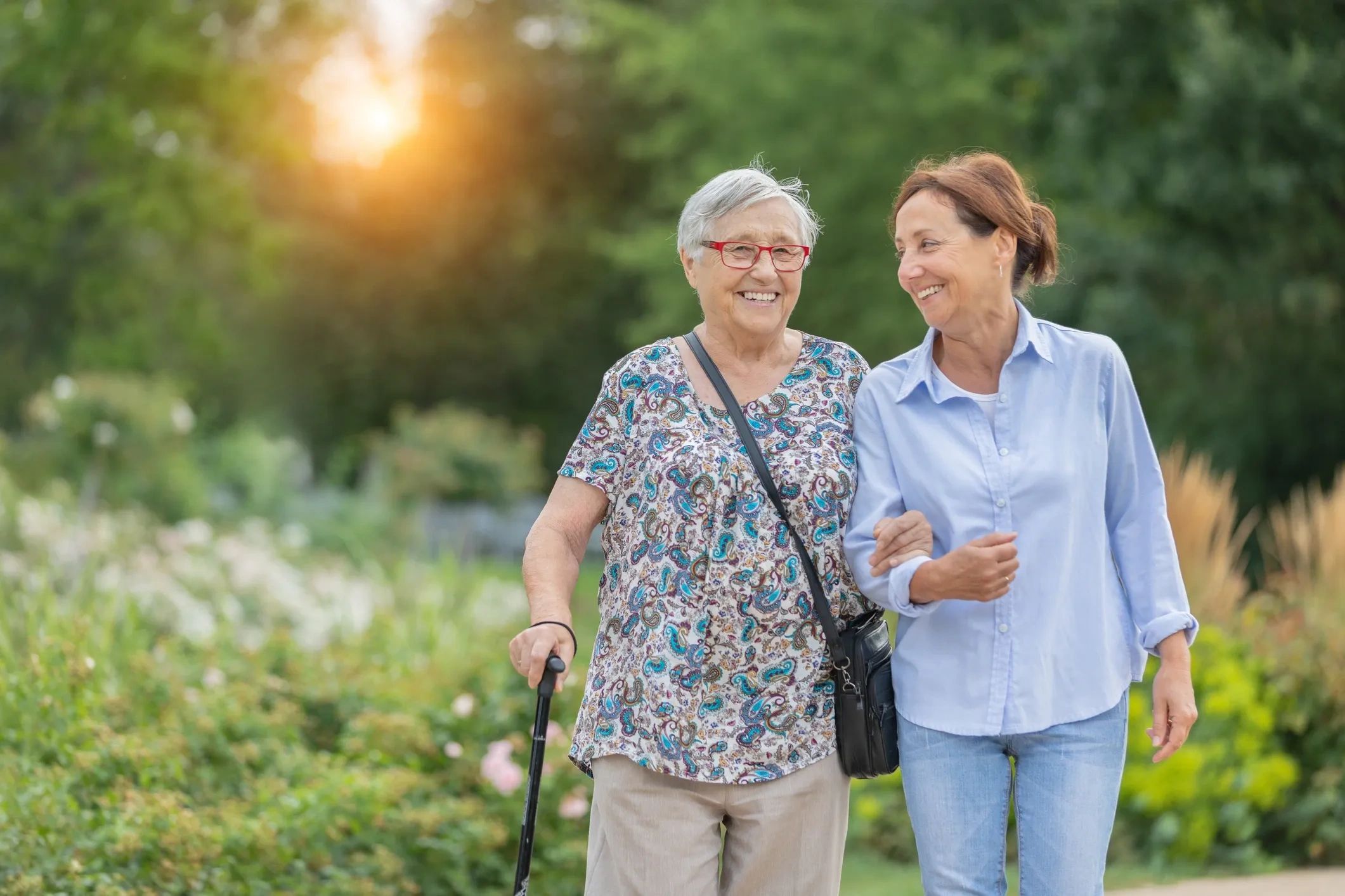 Two women walking together outdoors, smiling and enjoying each other's company.