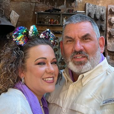 Smiling couple posing indoors with decorative background.