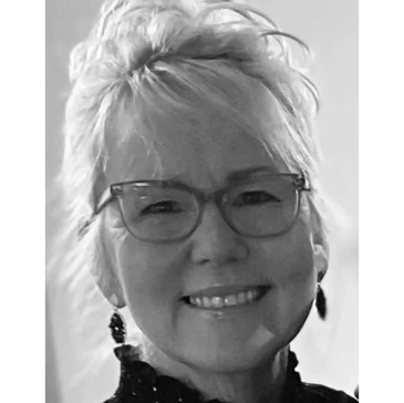Smiling elderly woman with glasses and earrings in black and white.