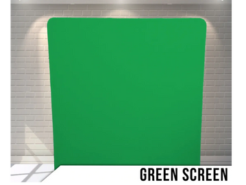 A green screen setup against a white brick wall with overhead lights.