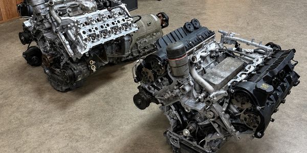 Two disassembled car engines on a garage floor.