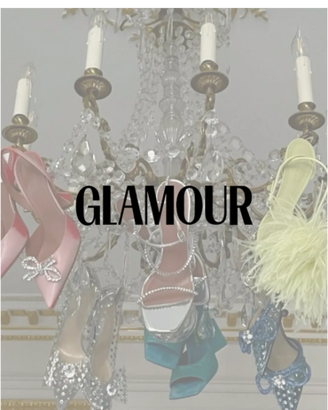 Elegant designer shoes hanging from a crystal chandelier with the word 'GLAMOUR'.