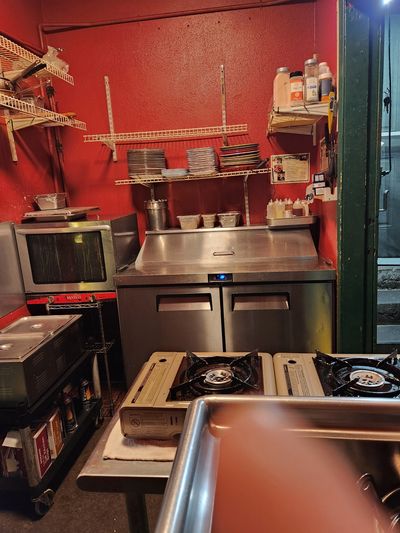 Compact kitchen with red walls and stainless steel appliances.