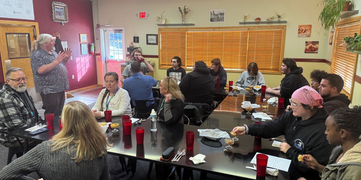 Group of people gathered around tables in a casual meeting or meal setting.