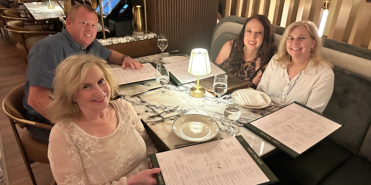 Four people dining together at a restaurant table with menus.