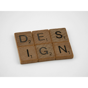 Wooden Scrabble tiles spelling the word 'DESIGN' on a white background.