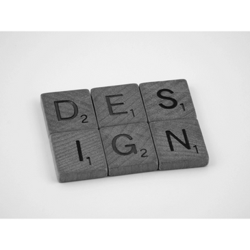 Wooden Scrabble tiles spelling the word 'DESIGN' on a white background.