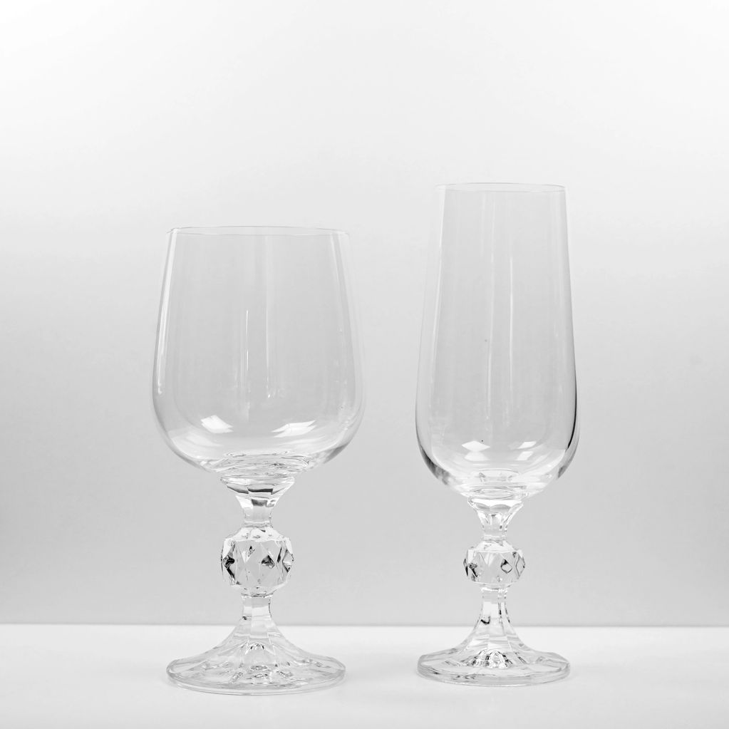 Two elegant crystal wine glasses with ornate stems on a plain background.