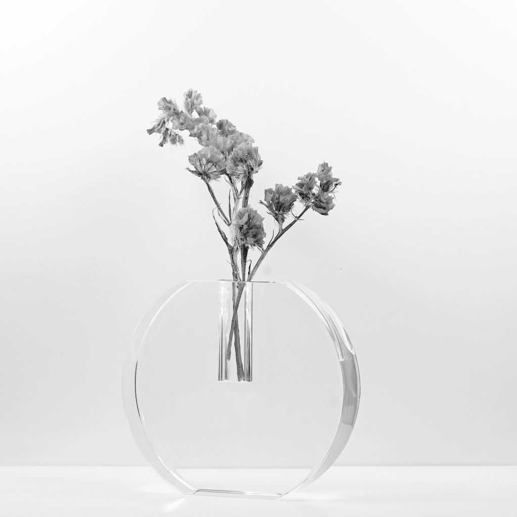 Minimalist round glass vase with delicate dried flowers.