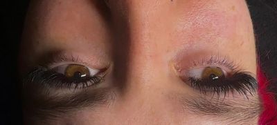 Close-up of a face focusing on two eyes with different eyelash styles.