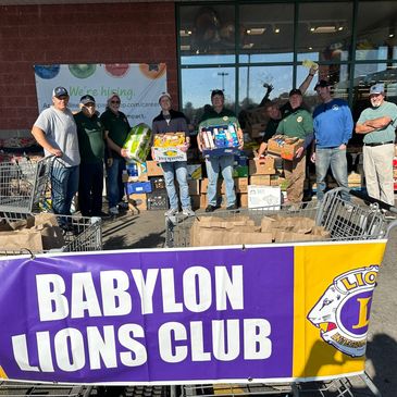 Members of Babylon Lions Club with donated food outside a store.