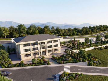 Modern two-story building surrounded by greenery and a mountainous backdrop.