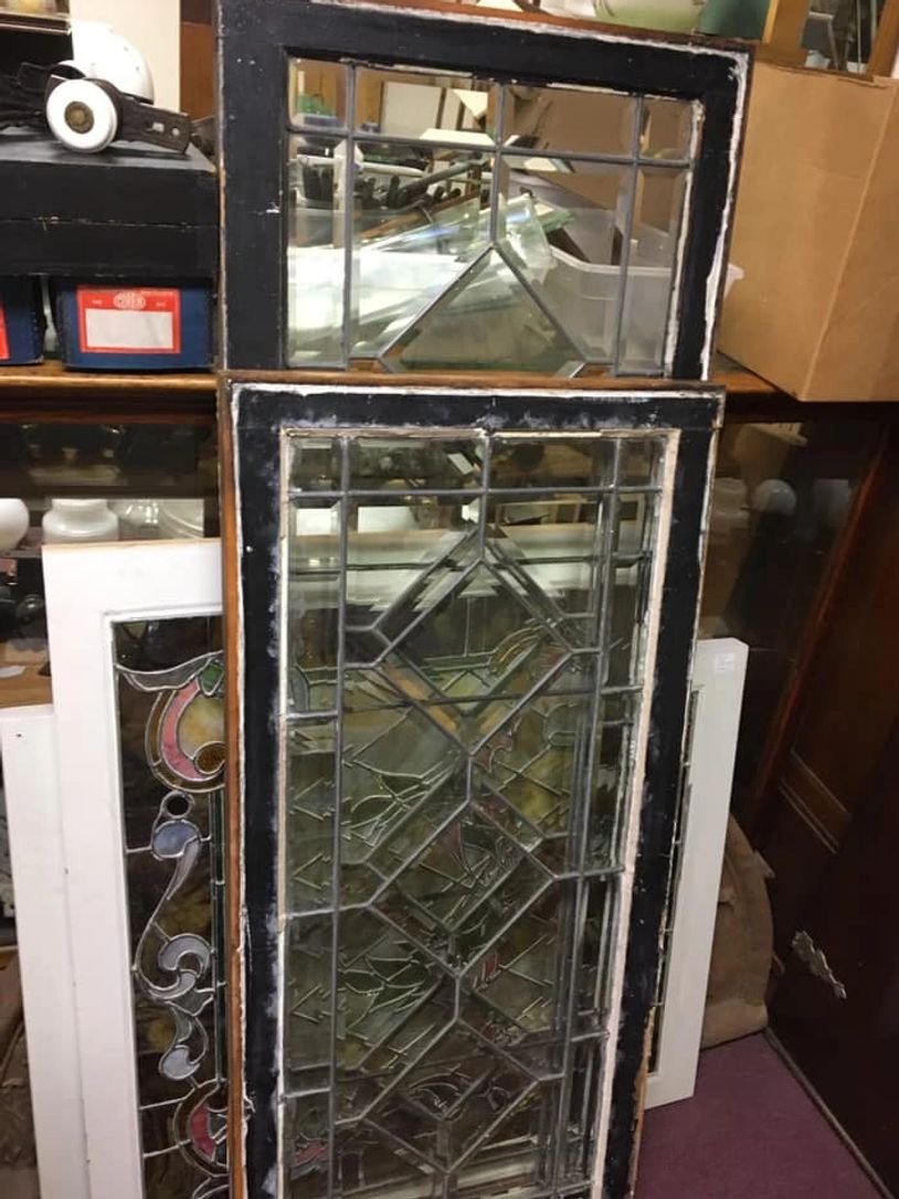 Two vintage stained glass window panels with intricate geometric designs.
