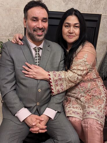 A couple warmly embraces, dressed in formal and traditional attire.