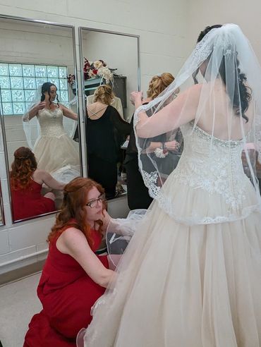 Bride gets help adjusting her wedding dress before the ceremony.