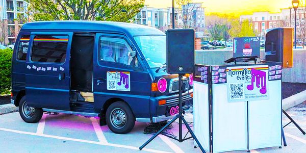 A DJ van setup with speakers and a booth for outdoor events.