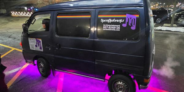 A black van with purple underglow lights parked at night.