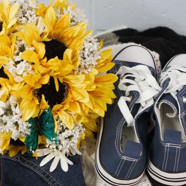 A colorful, quality photo of a sunflower bouquet next to a pair of blue sneakers.