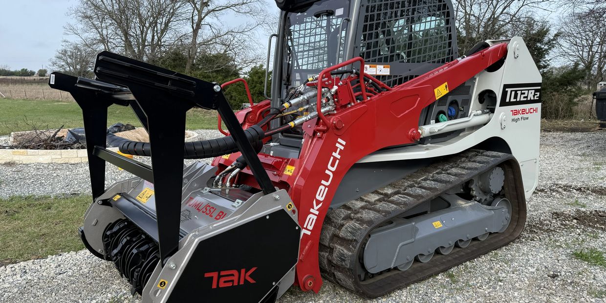 A red and white Takeuchi TL12R2 tracked skid steer loader with a TAK attachment.