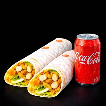 Two chicken wraps and a can of Coca-Cola on a black surface.