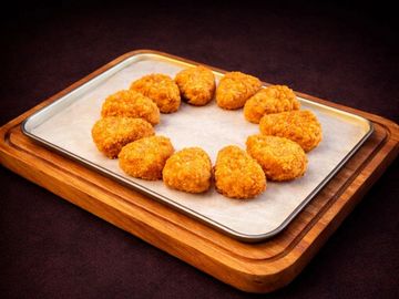 Golden, crispy chicken nuggets arranged in a circle on a tray.