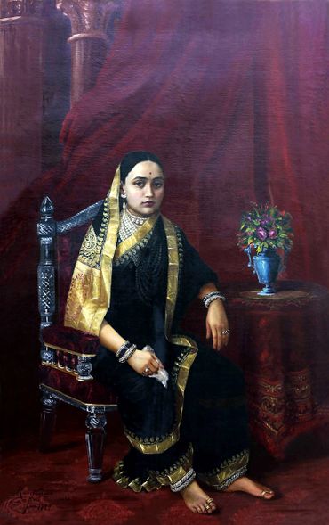 A regal woman in traditional Indian attire seated on an ornate chair.
