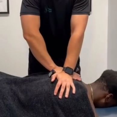 A therapist performs a back massage on a client lying face down.
