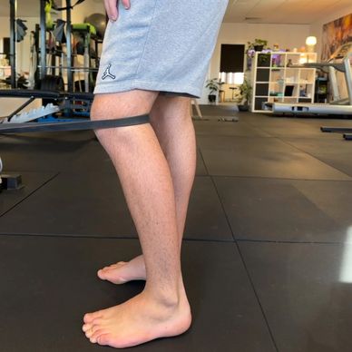 Person exercising legs with resistance band in a gym.