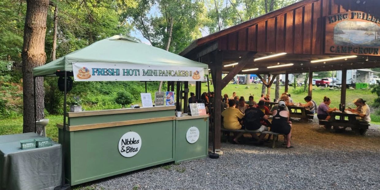 Outdoor pancake stand with picnic seating under a wooden pavilion.