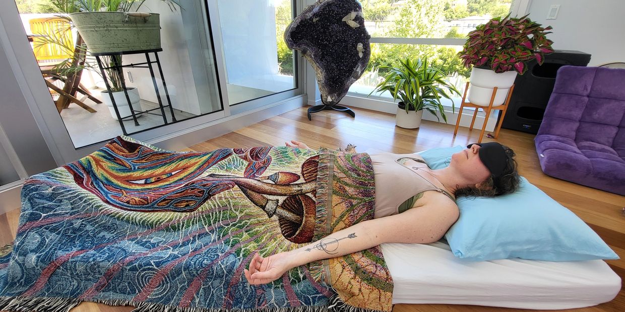 Person lying down on a mat with their eyes closed.