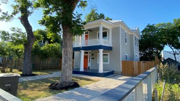 Two-story house with a porch and trees.
