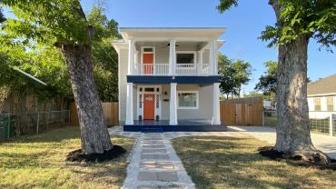 Two-story house with a bright orange door.