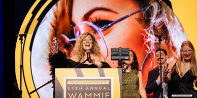 Woman speaking at the 37th Annual Wammie Awards ceremony.