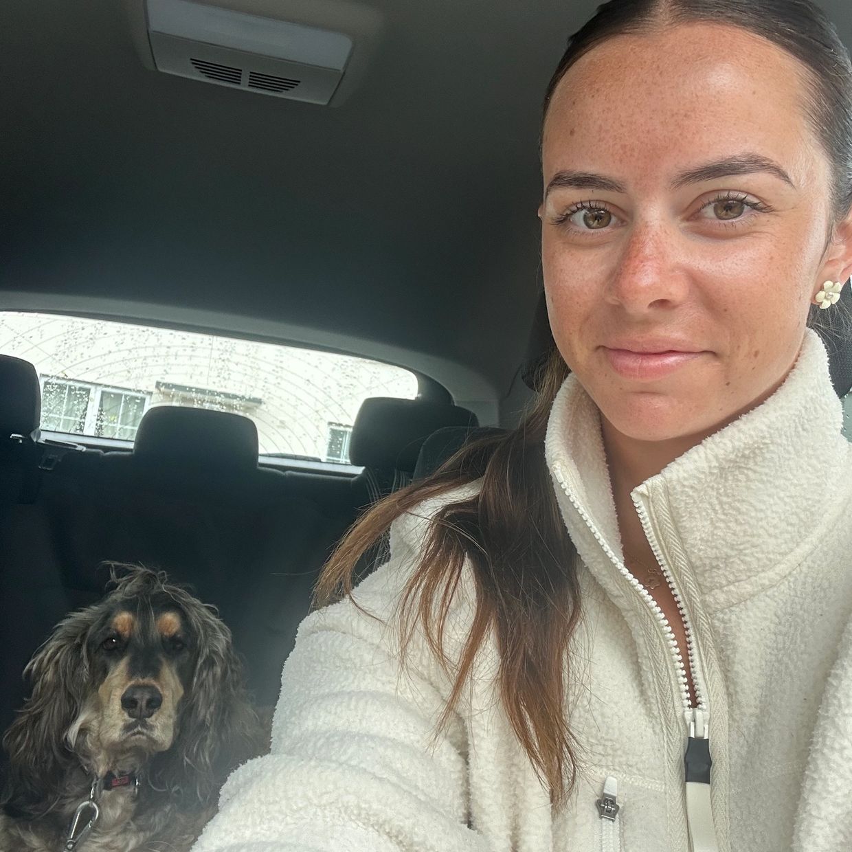 Woman and dog sitting in a car.