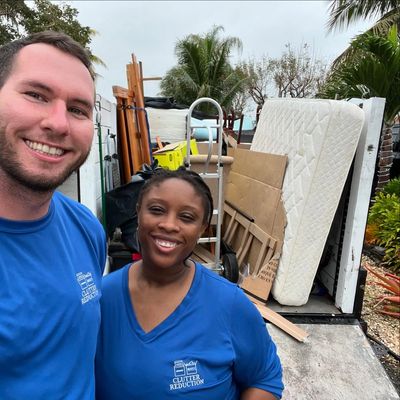 Husband and wife posing in front of trailer full of junk
