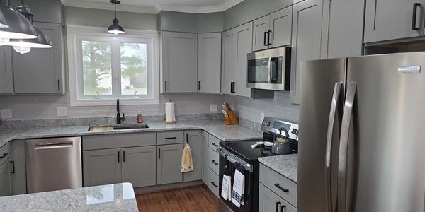 Modern kitchen with gray cabinets and stainless steel appliances.