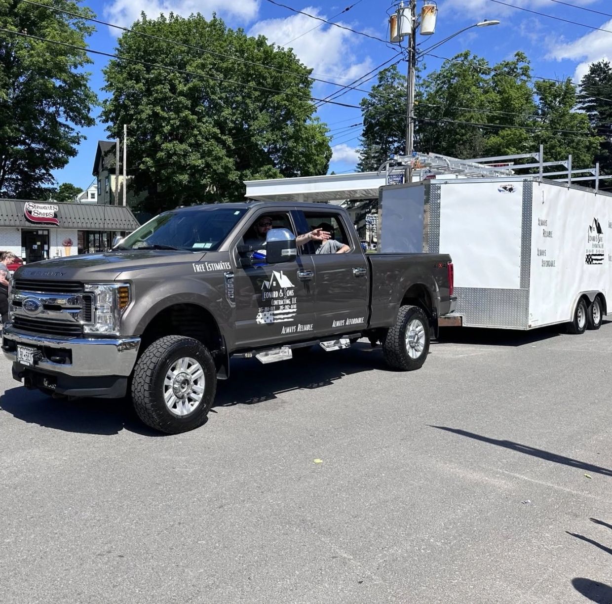 Ford pickup truck towing a large white trailer with business branding.