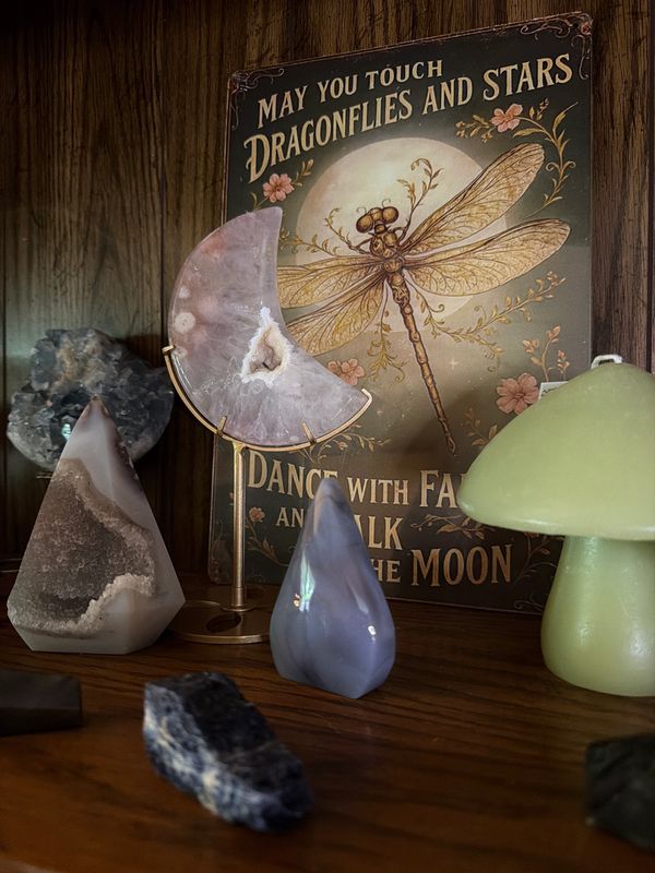 Decorative crystals and a dragonfly-themed inspirational sign on a wooden shelf.