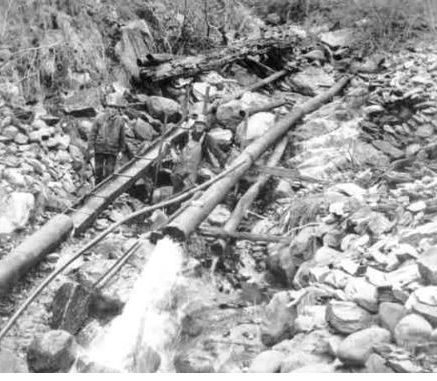 Workers operating a water pipe system in a rocky terrain.