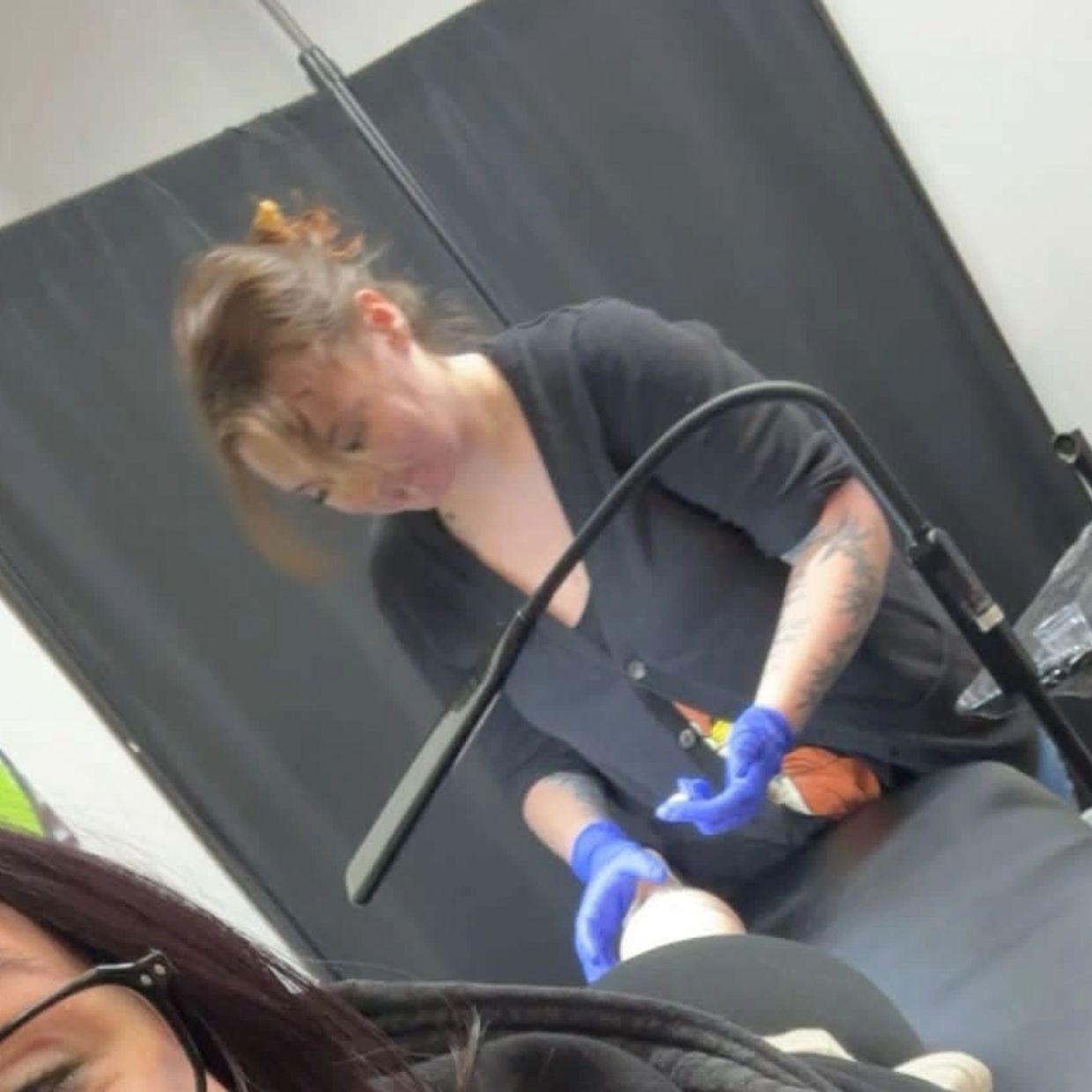 Tattoo artist working on a client's leg.