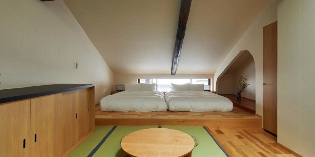 Guest enjoying Japanese tea ceremony in machiya room with exposed beams