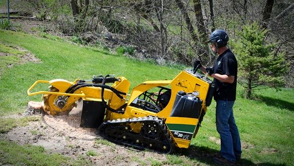 Operator running the yellow stump grinder on a lawn