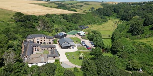 A countryside estate with multiple buildings surrounded by lush greenery and fields.