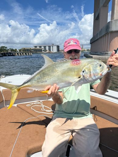 Man proudly holds a large fish on a boat under a partly cloudy sky.