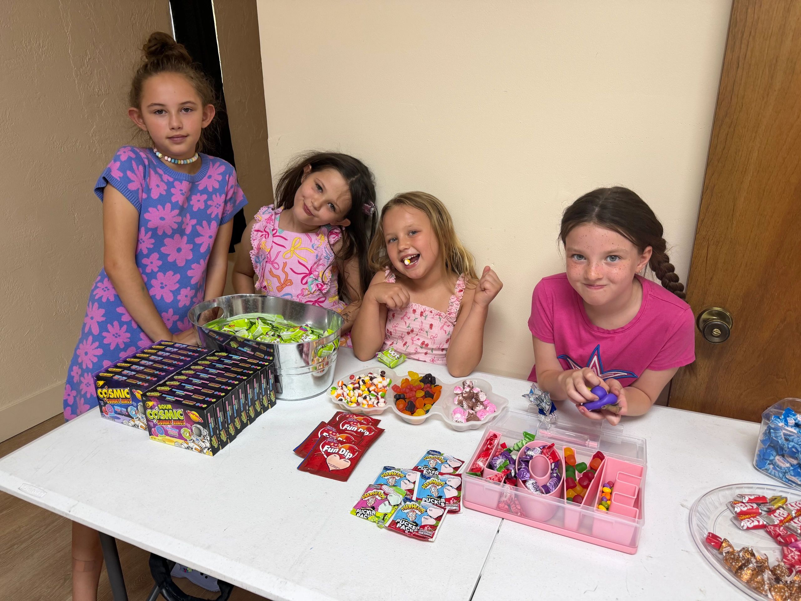 Four girls enjoying a candy table with various sweets and snacks.