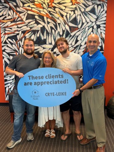 Four people smiling and holding a sign appreciating clients.