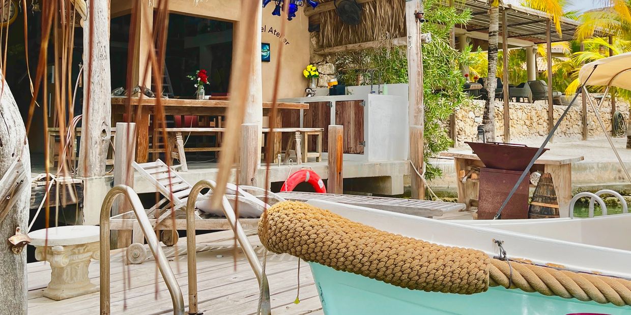 A serene dockside scene with a boat and rustic wooden seating area.