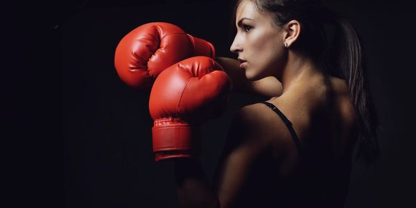 Woman in a fighting stance, with two boxing gloves on ready for her Boxercise session.